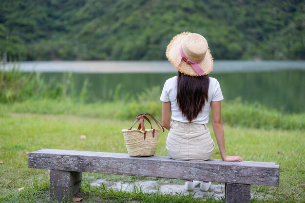 石のベンチに座って湖を見ている女性