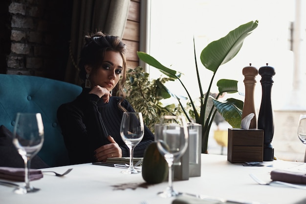 Woman sit at the table in cafe or restaurant and drink a coffee