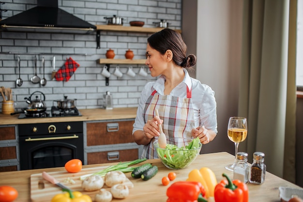 Woman sit on table and cook in kitchen