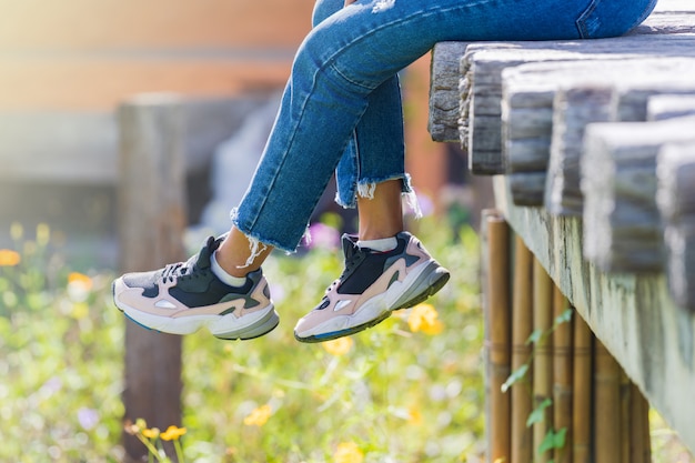 La donna si siede sul ponte di legno e sulle gambe d'attaccatura nel giardino floreale