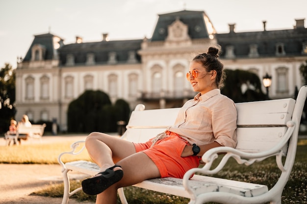 Photo a woman sits on a bench in front of a castle.