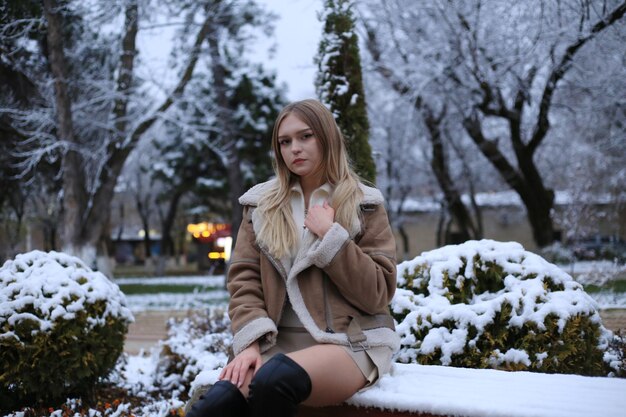 a woman sits on a bench in the snow