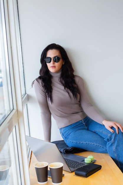 A woman sits on a bench wearing a gray turtleneck and jeans.