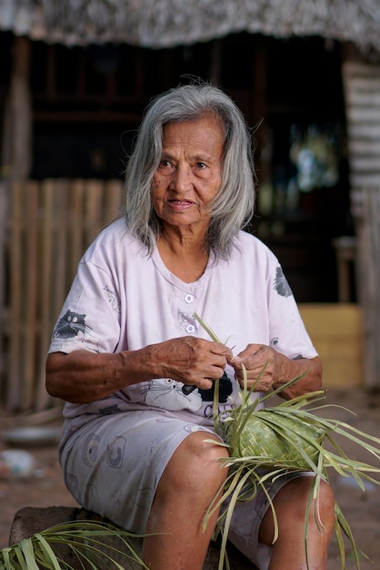 A woman sits on a bench with a bunch of leaves on her head.