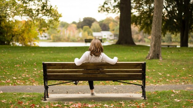 Photo a woman sits on a bench with her back to the camera