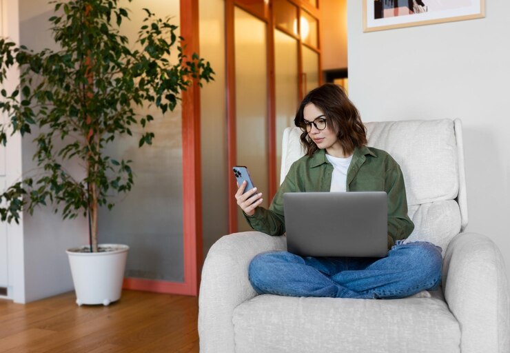 Photo a woman sits on a chair with a laptop and a tree in the background.