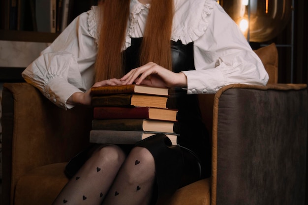 A woman sits in a chair with a stack of books with a heart on her shirt