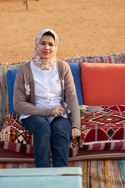 A woman sits on a couch in the desert.