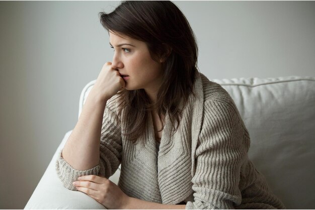 A woman sits on a couch and looks at the camera.