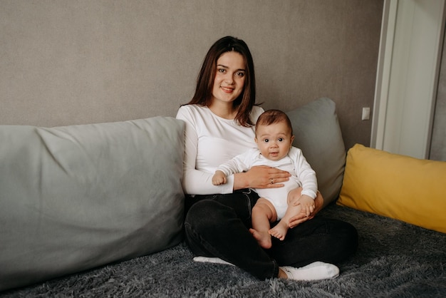 A woman sits on a couch with a baby on her lap.