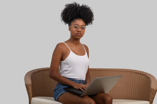 A woman sits on a couch with a laptop