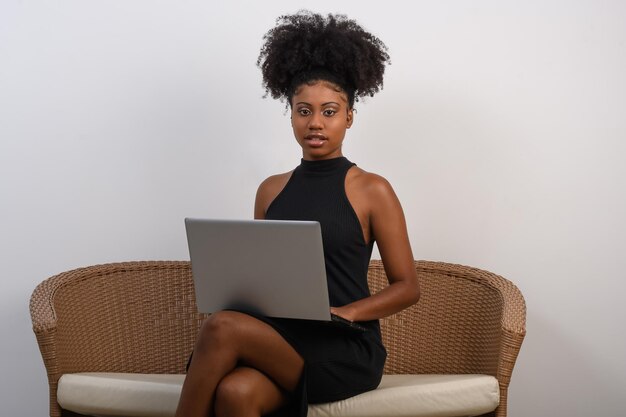 A woman sits on a couch with a laptop