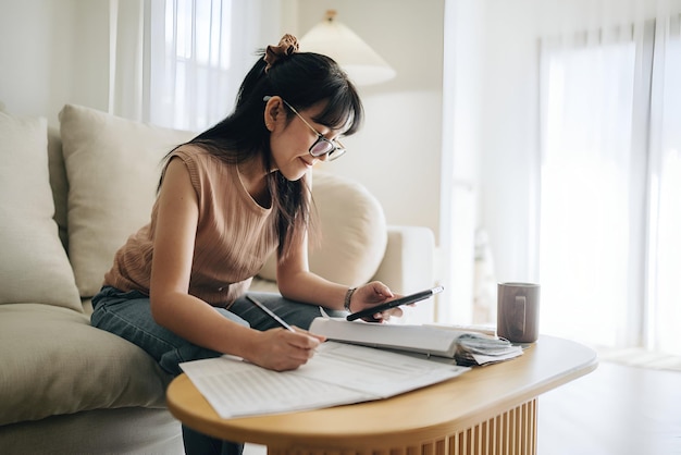 a woman sits on a couch working on phone with a cup of coffee