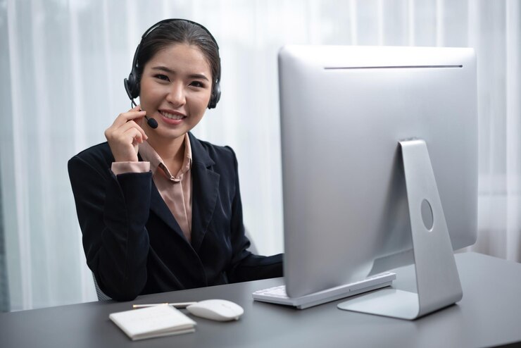 Photo 一位女士坐在辦公桌旁,手上有電腦和耳機.