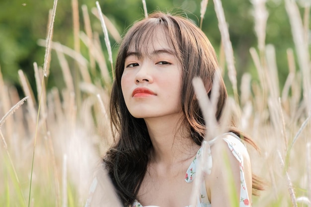 A woman sits in a field of tall grass and looks at the camera.