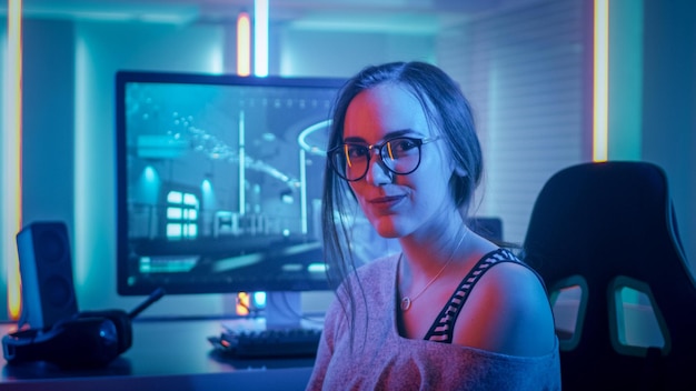 A woman sits in front of a computer monitor with a lit up blue light.