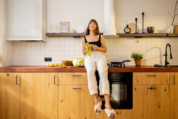 Woman sits on a kitchen table top with healthy food at home