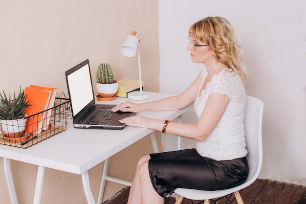 a woman sits in an office and works at a laptop remote work copywriter or manager