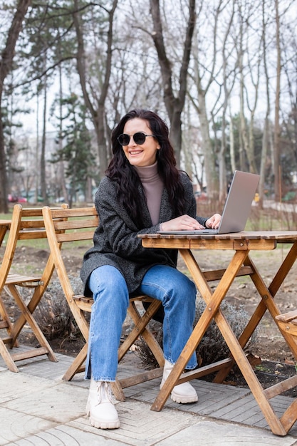 A woman sits in a park with a laptop.