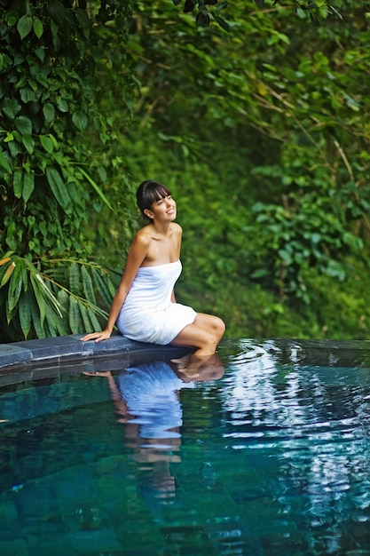 A woman sits in a pool of water and looks at the camera