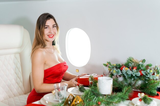 Woman sits in private jet by illuminator decorated for christmas new years eve flight holiday and