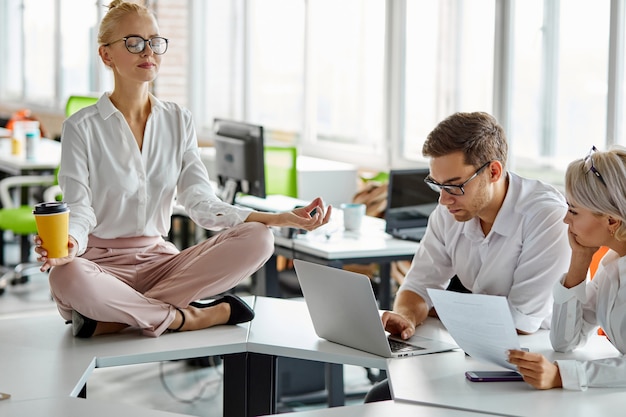 woman sits relaxing while other have brainstorm at work