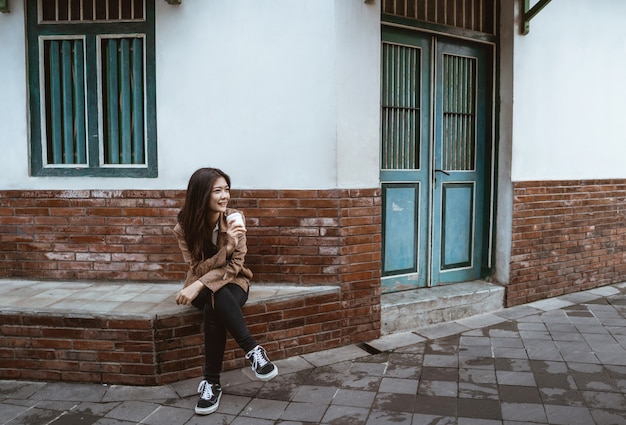 Woman sits on road side enjoyinging a cup of coffee