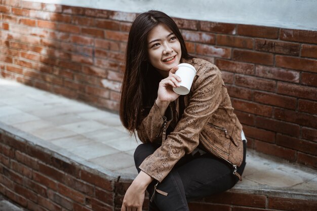 Woman sits on road side enjoyinging a cup of coffee