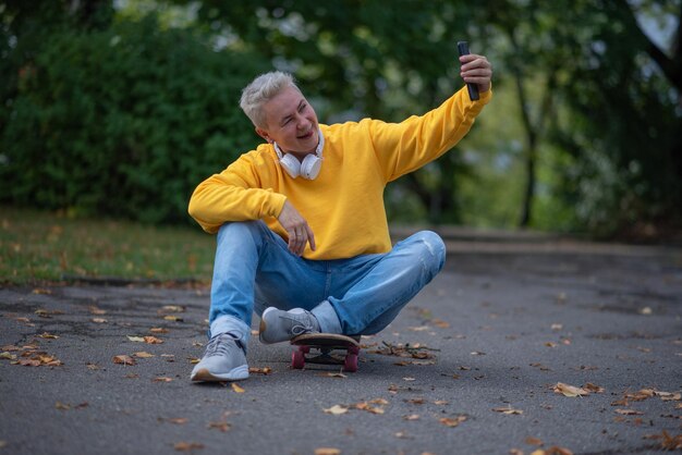 Photo a woman sits on a skateboard and looks into her phone and does salfy