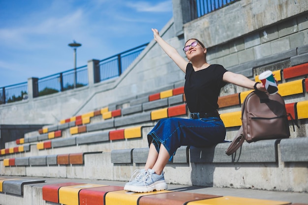 Photo woman sits on steps and holds a disposable cup of coffee