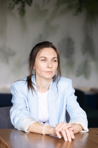 A woman sits at a table in a cafe and reads a book.