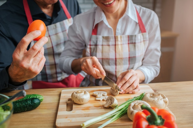 Woman sits at table and cuts mushrooms