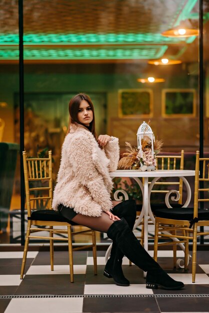 A woman sits at a table in front of a cafe with a gold sign that says'i love you '