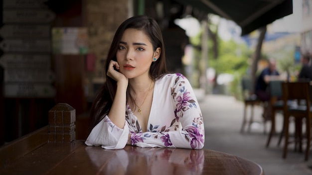 a woman sits at a table with a flowered top