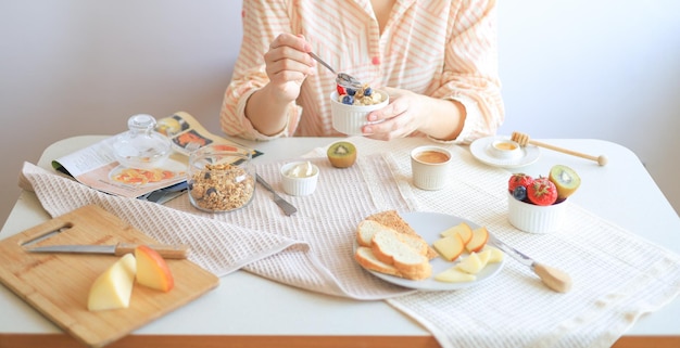 A woman sits at a table with healthy food and eats her breakfast