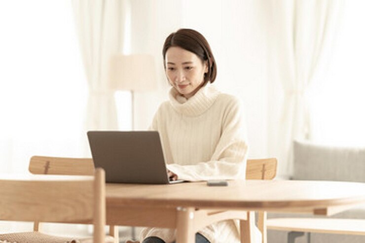 Photo 一位女士坐在桌子旁,膝上有一台笔记本电脑和一本书