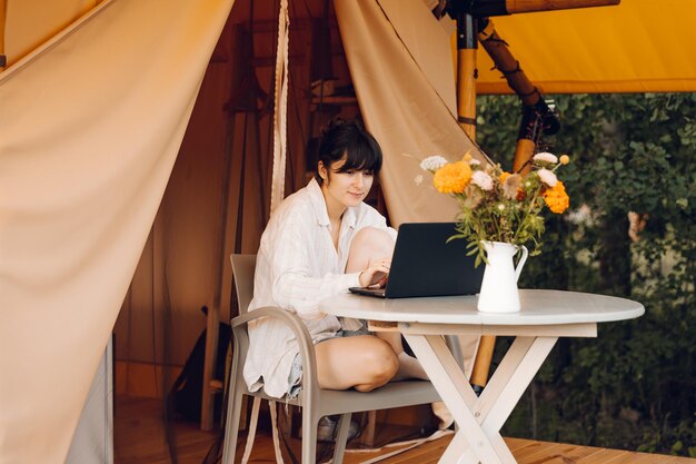 a woman sits at a table with a laptop on her lap