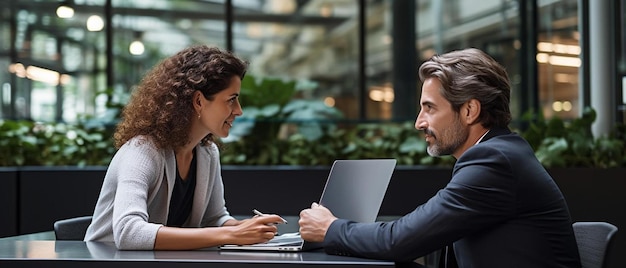 a woman sits at a table with a laptop and a man with a woman in a suit on the back of her laptop