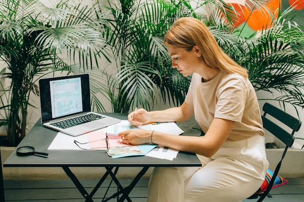 a woman sits at a table with a laptop and a map on it