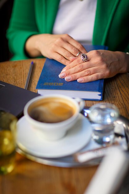 A woman sits at a table with a notebook titled 2023 espresso on it