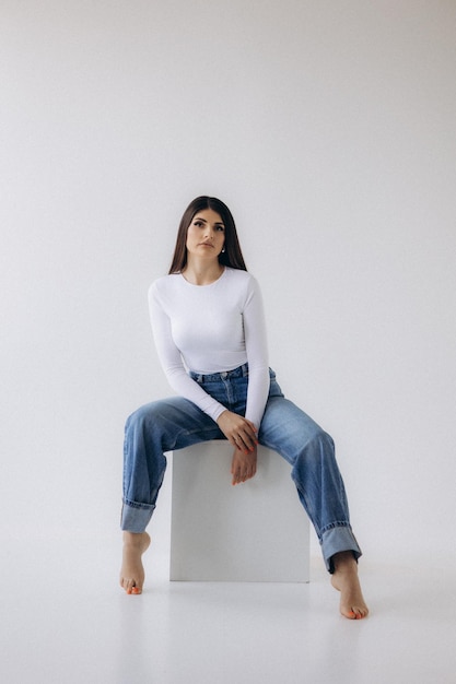 a woman sits on a white chair with her legs crossed