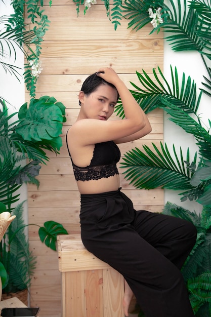 A woman sits on a wooden box in front of a plant with the word love on it.