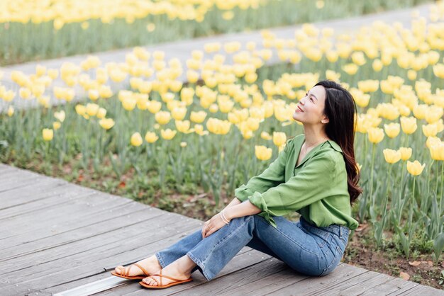 Woman sitting against flowers in field