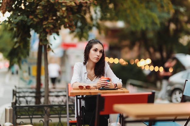 거리에 테이블에 앉아 여자입니다. 저녁 따뜻한 도시. 고품질 사진