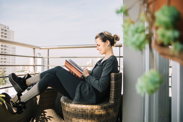 Photo woman sitting in balcony looking at photo album