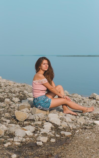 Photo woman sitting on beach against clear sky