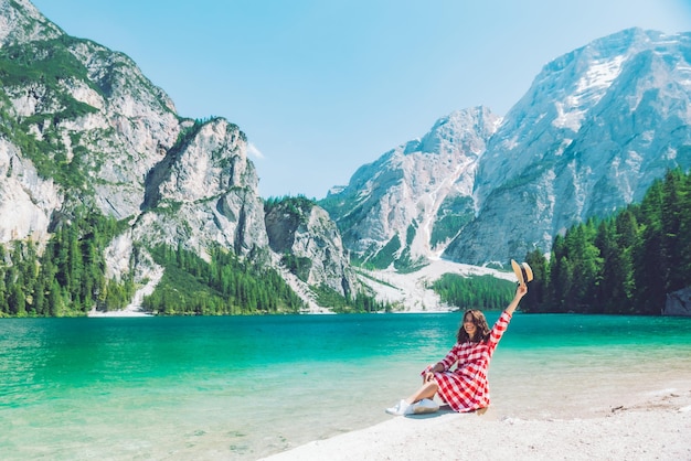 山の湖の夏のビーチに座っている女性