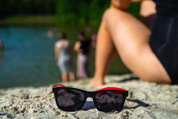 Foto donna seduta in spiaggia con occhiali da sole vicino all'ora legale