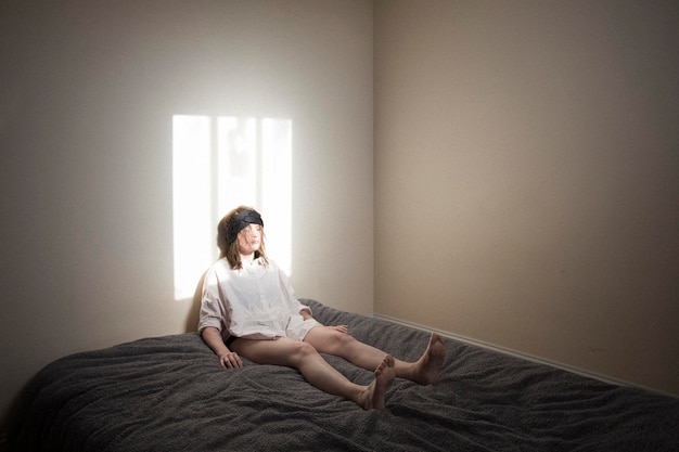 家の壁に寄りかかってベッドに座っている女性