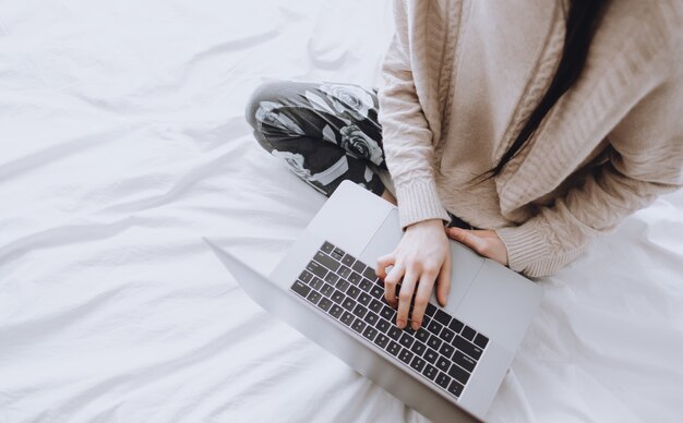 Женщина сидит в постели и работает с ноутбуком